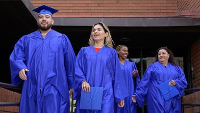 Rio Salado College graduates walking out of a building in caps and gowns