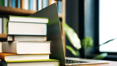 A stack of books next to an open laptop