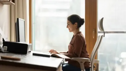 Woman sitting in ergonomic chair while working on a computer in her office