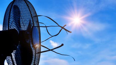 A fan blowing air outdoors under a hot sun