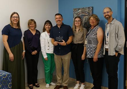 Institutional Integrity and Compliance Office staff holding the award