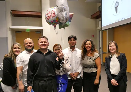 Yeison Ramirez Mendez stands with a group of supporters holding congratulatory balloons during an induction ceremony.