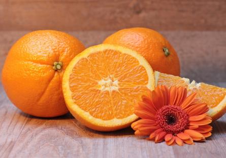Four oranges and an orange-colored flower